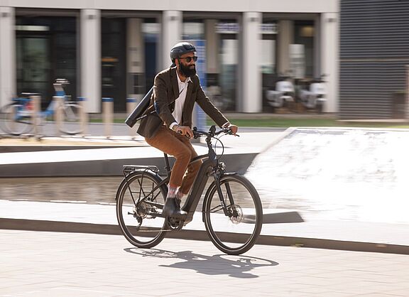 Ein Pendler fährt auf seinem elektrischen Fahrrad durch das Stadtgebiet. 