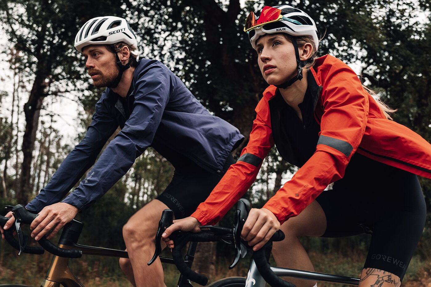 Gorewear Zwei Radfahrende fahren nebeneinander in sportlicher Kleidung.
